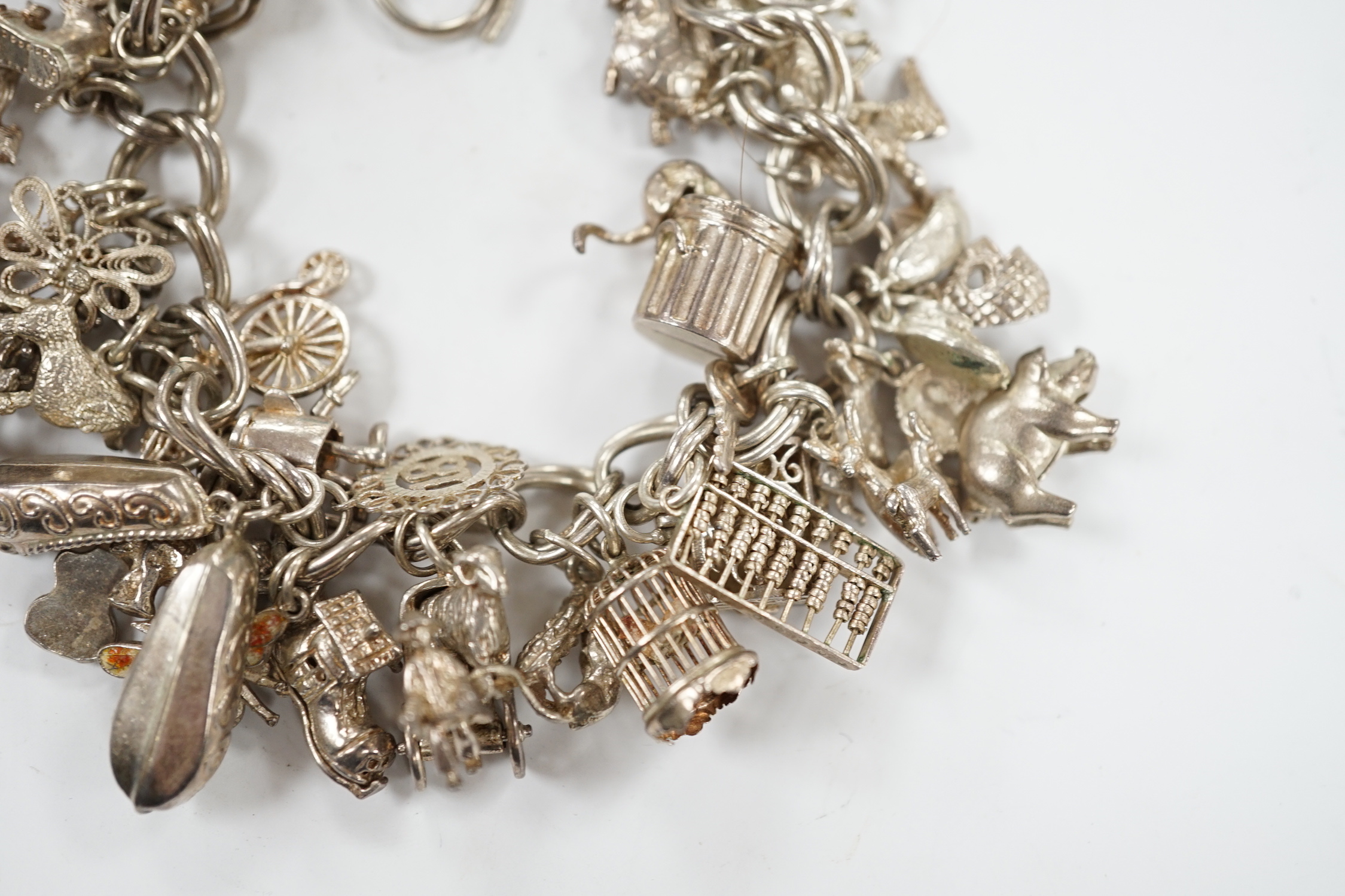 A 1970's silver charm bracelet, hung with assorted charms including birdcage, abacus, piglet, etc. and another silver charm bracelet with loose charms.